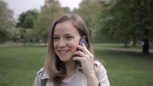 Woman talking at the phone in a public park, London, UK