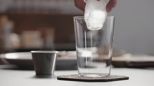 Slow Motion Man Put Ice Into Tumbler Glass to Make Spritz Drink on Concrete Countertop