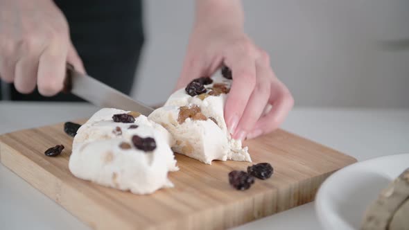 Lady cook cuts delicious sweet pakhlava into slices with knife on brown wooden cutting board