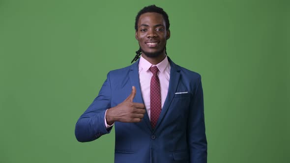 Young Handsome African Businessman with Dreadlocks Against Green Background