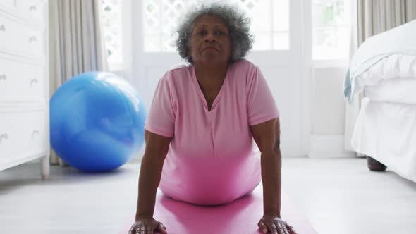 Senior african american woman performing exercise in bedroom at home