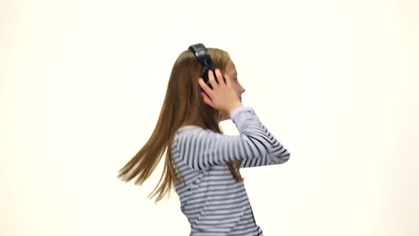 Child on Headphones Jumps To Music, White Background. Slow Motion