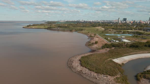 Aerial backwardement of Vicente Lopez costal walk, revealing the city in background