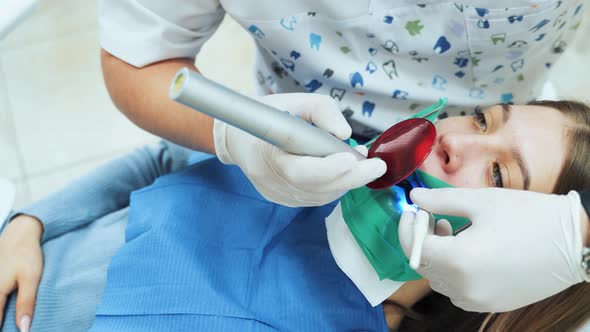 The girl in the office at the dentist. Dental restoration and material polymerization with UV light.