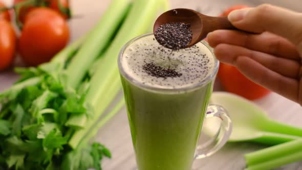 Slow Motion Video Chia Seeds Pour Into a Glass of Celery Smoothie with Sprig of Tomatoes on