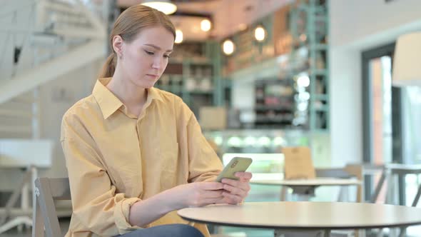 Serious Young Woman Using Smartphone in Cafe 