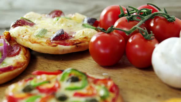 Italian pizza on wooden table with vegetables and spices