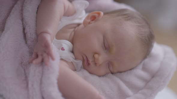 Closeup Sleeping Caucasian Little Infant Lying in Pink Blanket with Woman Kissing Cheek in Slow