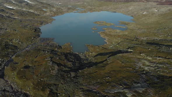 Hardangervidda glacial lake with glacier in background, Norway, aerial reveal