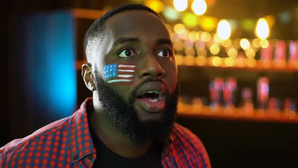 Nervous Afro-American Soccer Fan With Flag on Cheek Unhappy With Game Result