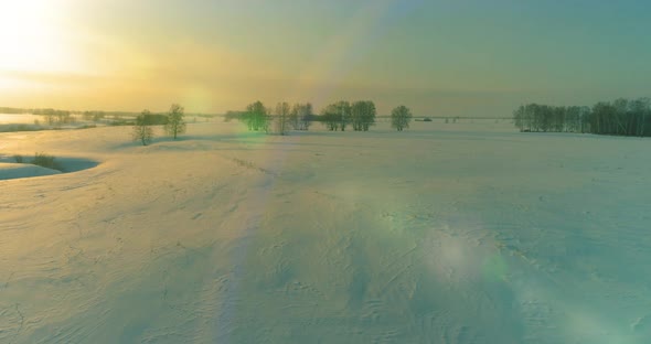 Aerial View of Cold Arctic Field Landscape Trees with Frost Snow Ice River and Sun Rays Over Horizon