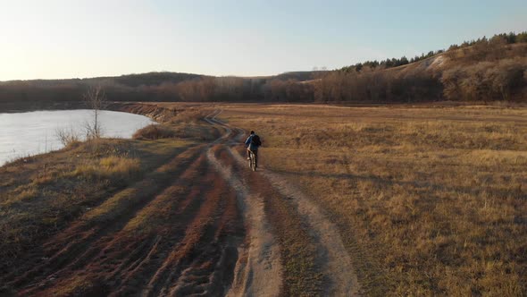 Aerial View of a Cyclist Riding on His Bicycle in Mountain at Sunset.