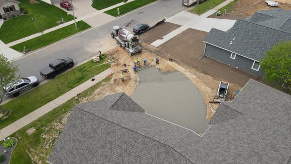 Fast pace of concrete crew working with wet cement to finish the long driveway in new home.