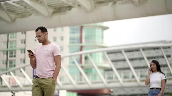 Focused Young Man Walking on Street and Looking at Phone