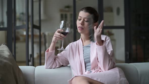 Young woman turned off boring tv, throwing out remote control and drinking wine