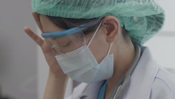 Doctor or nurse suffering from a headache and rubbing her temples while working.