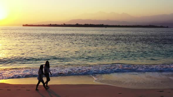 Beautiful women best friends on luxury coast beach wildlife by blue sea with clean sandy background 