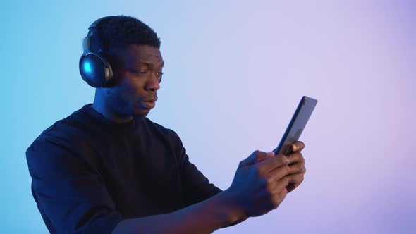 African American Man Wearing Headphones Holding a Phone in His Hand