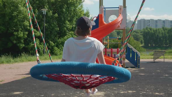 Slow Motion of Young Caucasian Woman Swinging on Big Blue Wicker Nest Swing