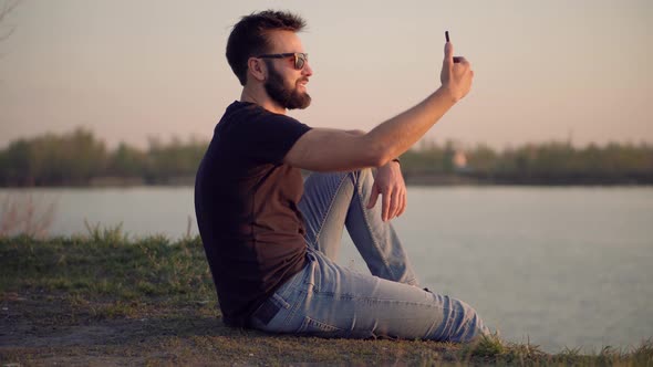 Man Holding Mobile Phone Using Mobile App Taking Picture. Male Relaxing On Nature. Man Takes Photo.