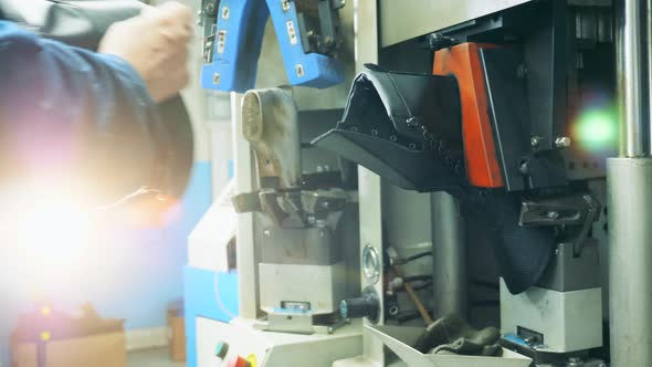 Factory Worker Is Putting Material Into a Machine To Make Shoes