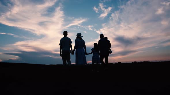 Silhouette of a Happy Family Holding Hands Walking at Sunset