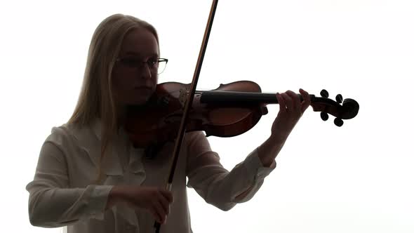 Blonde Woman in Glasses and White Blouse Plays with Bow and Fingers on Strings of the Violin in Dark