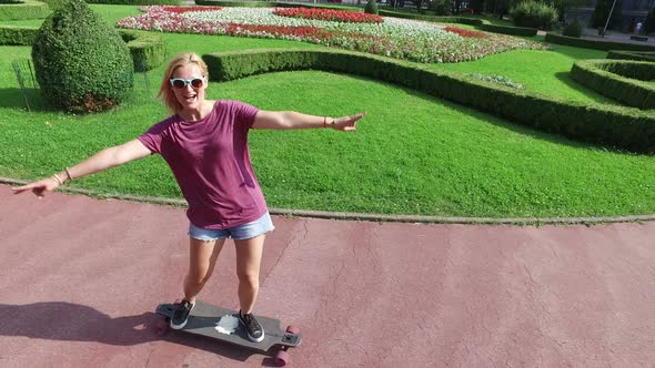 Cheerful blonde woman riding on a longboard