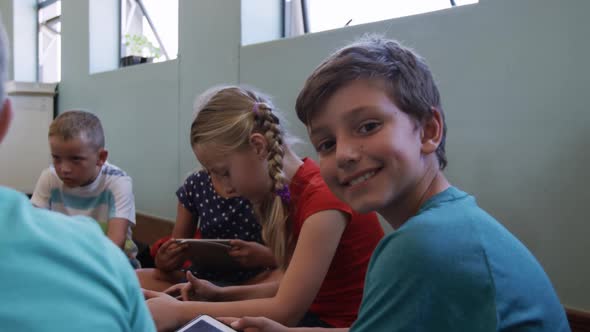 Boy smiling while using digital tablet in the class