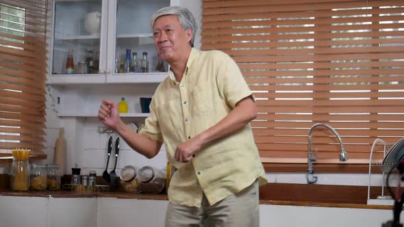 Portrait of Asian senior man happy smiling dancing cooking in the kitchen at home.