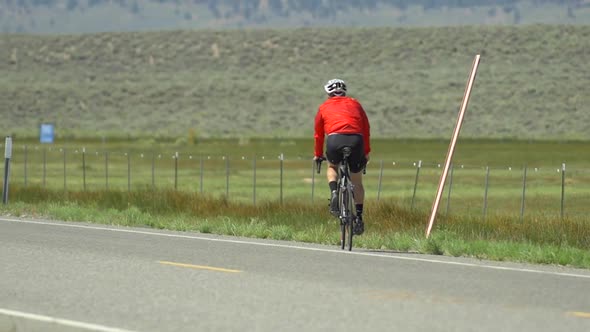 A man road biking on a scenic road.