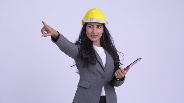 Young Happy Persian Businesswoman As Engineer Directing While Holding Clipboard