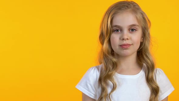 Pretty Little Girl Winking at Camera on Isolated Yellow Background, Template