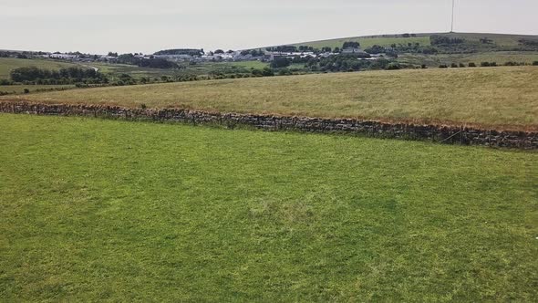 Drone ascending over a field in Dartmoor National Park in Devon England. Farmland with separating st