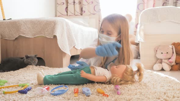 Beautiful Little Girl Playing Doctors with Doll at Home