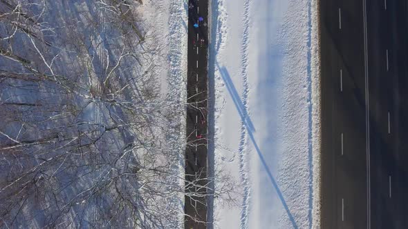 Athletes Jogging on Path near City Road in Winter