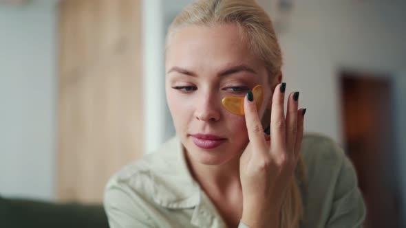 Concentrated blond woman sticking patches to eyes