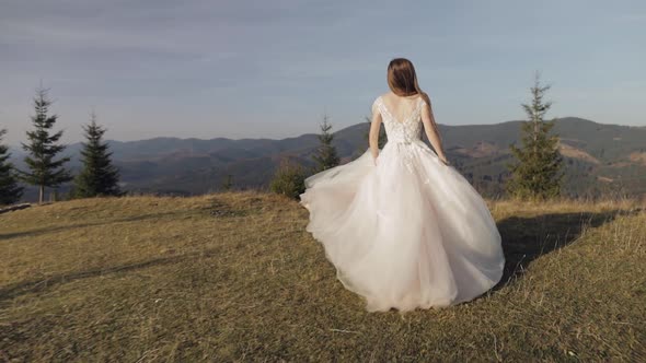 Beautiful and Lovely Bride in Wedding Dress Running on Mountain Slope