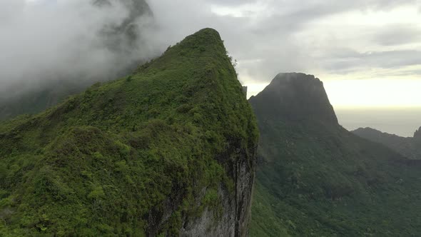 Aerial flying sideways over an exuberant mountain ridge with a dramatic sky on background