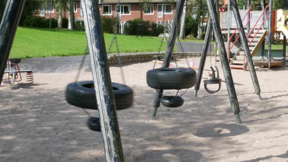 an Empty swing made up of used car tires swinging on a playground in the town of Partille outside of