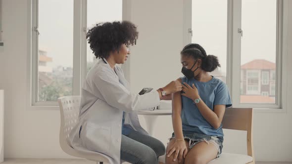 African american doctor is applying plaster to a child's shoulder after being vaccinated.