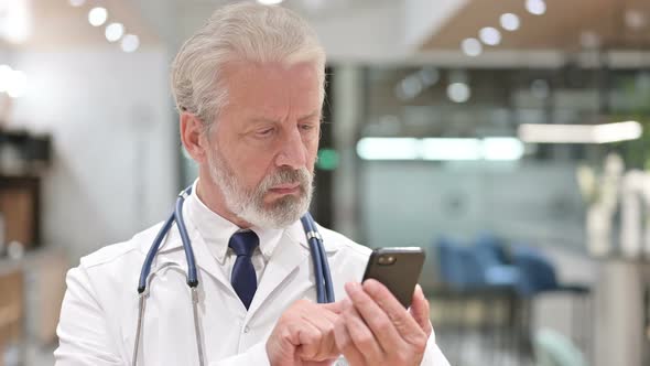 Serious Senior Old Doctor Using Smartphone 