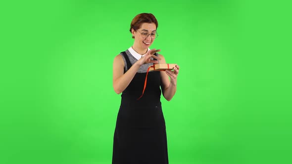 Funny Girl in Round Glasses Is Opening the Gift, Very Surprised and Rejoicing. Green Screen