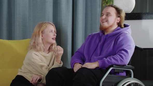 Happy Couple of Blonde Woman and Man in a Wheelchair Talking and Laughing