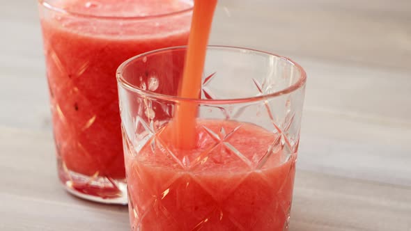 Fresh healthy fruit smoothie mocktail drink being poured into the glasses