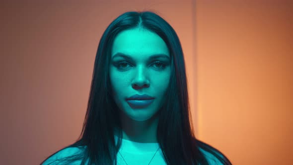 Attractive Brunette Woman Opens Her Eyes and Looks Seductively in Neon Lighting