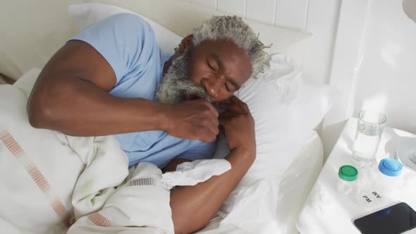 Senior man with tissue coughing in the bed at home