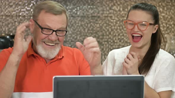 Adorable Brunette and Her Father Stare Intently at the Laptop Screen