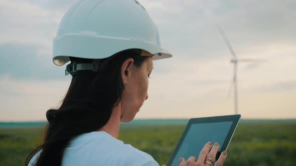 Woman Engineer Working in Wind Turbine Electricity Industrial at Sunset