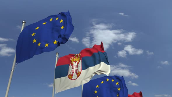 Waving Flags of Serbia and the EU on Sky Background alt